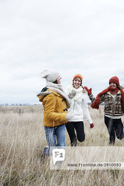 Female friends enjoying in field in warm clothing