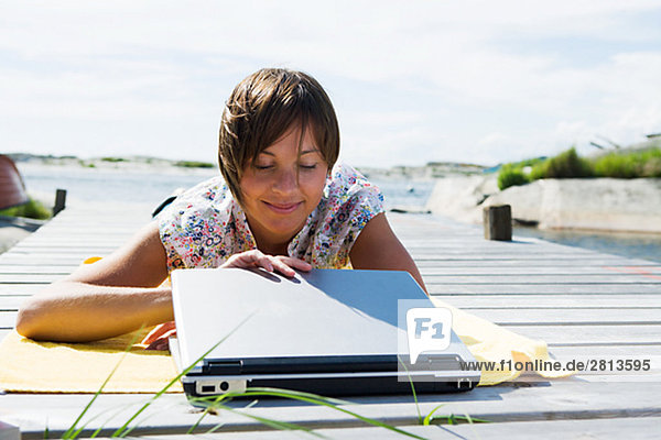 Eine skandinavische Frau mit einem Laptop in den Schären Schweden.