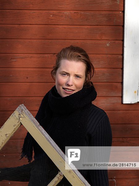 A young woman holding a window frame Sweden.