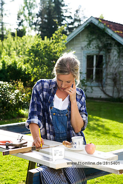 A woman doing carpentry in a garden Sweden.
