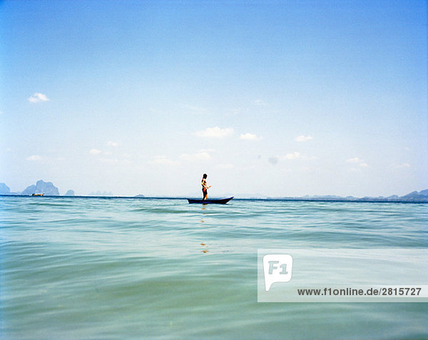 Ein Mann in einem kleinen Boot auf das blaue Meer Thailand.