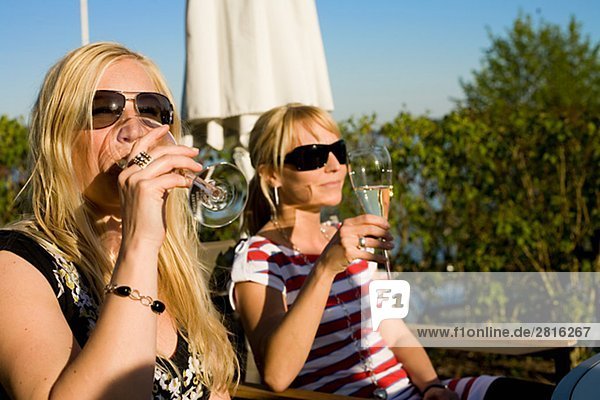 Two women drinking wine in the sun Sweden.