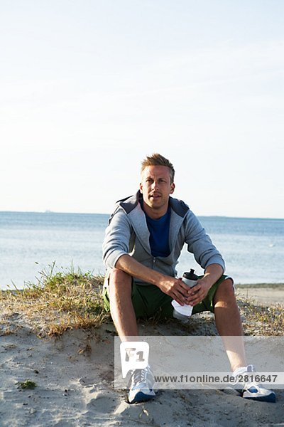 A man resting after jogging on the beach Malmo Sweden.