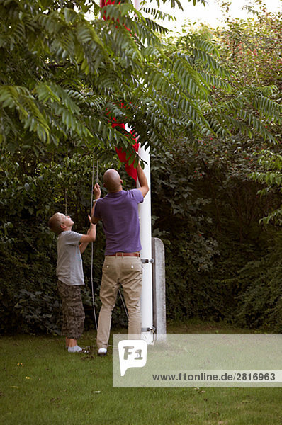 Ein Mann und ein Junge Hochziehen der dänische Flagge Kopenhagen Dänemark.