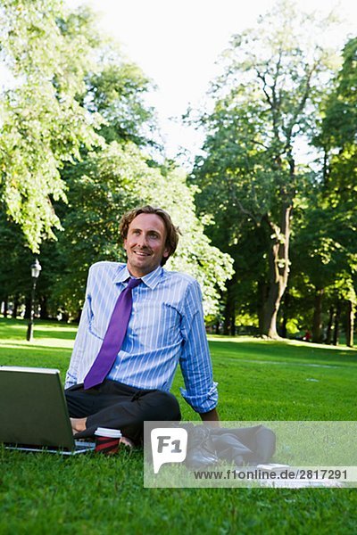 A man with a laptop in a park Sweden.