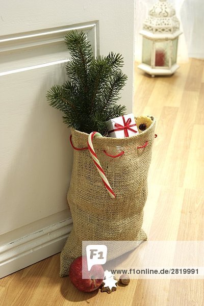 Sack of Christmas tree and presents near door