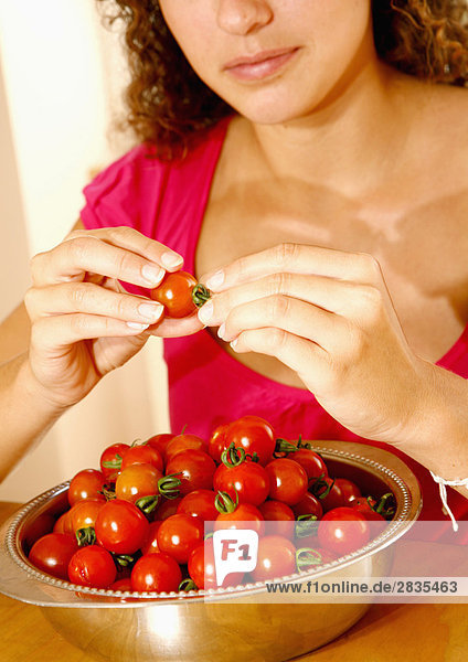 Frau nehmen die Stiele aus Tomaten