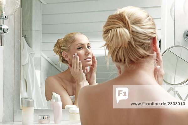 Woman applying lotion in bathroom