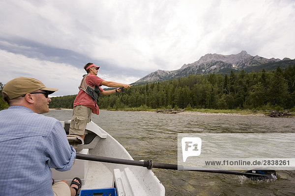 Young men fly fishing on the Elk River from a dory while guide watches  Fernie  East Kootenays  British Columbia  Canada.
