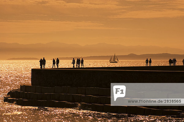 People walkng along the Breakwater at sunset  victoria  vancouver island  british columbia  canada.