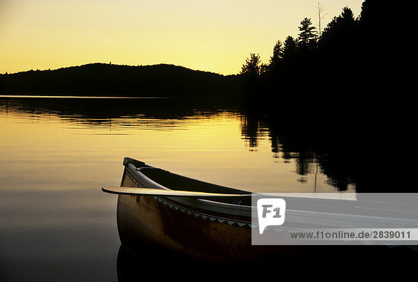 Die Sillhouette von Canoe als es ruht am Ufer eines Sees bei Sonnenuntergang auf Stand See in Alqonguin Provincial Park  Ontario  Kanada.