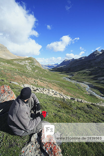 Male hiker enjoying the view and his morning coffee in the backcountry  looking over Dolomite Creek  Banff National Park  Alberta  Canada.
