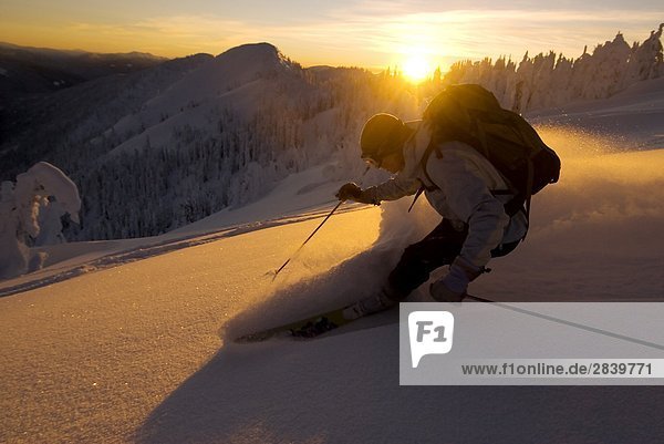 Frau Ski Instructor Hintergrundbeleuchtung mit Alpenglühen  Sonnenuntergang  Skifahren Pulver down Abend Ridge  Wildwasser-Skigebiet  Nelson  British Columbia  Kanada.