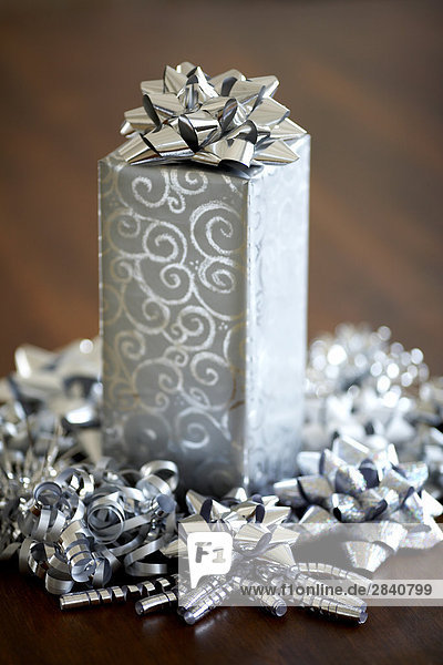 silver wrapped gift surrounded with silver ribbons and bows sitting on a wooden table  Montreal  Quebec  Canada.