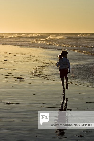 Young girl running along beach at Profitts Point near Darnley  Prince Edward Island  Canada.