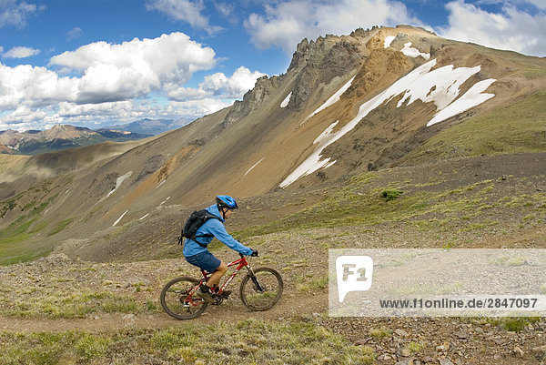 Mountain biker rides his bike up the trail to Deer Pass  Southern Chilcotin Mountains  British Columbia  Canada.