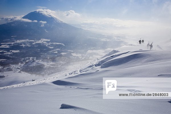 Skiers bootpacking on a ridge in the backcountry of Niseko  Japan