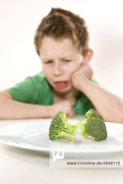 Boy disliking broccoli