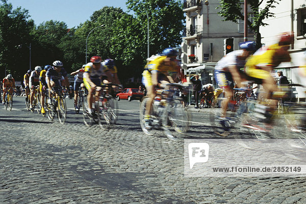 Cyclists racing on cobblestone street