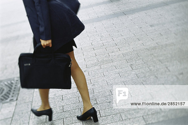 Businesswoman walking on sidewalk  cropped view