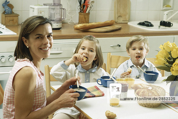 Familie beim Frühstück am Tisch sitzend  lächelnd vor der Kamera