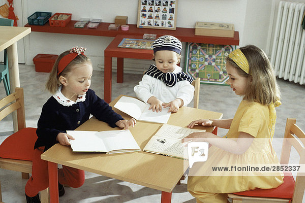 Children sitting around table with books