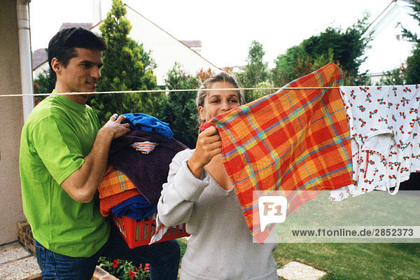 Ein Paar hängt die Wäsche an der Wäscheleine auf.