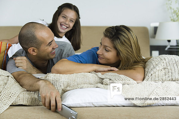 Family relaxing on bed together  man and woman smiling at each other