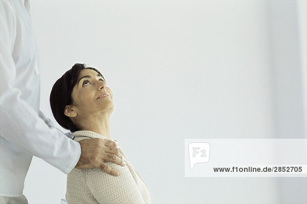 Woman sitting looking up at husband standing behind placing hands on her shoulders