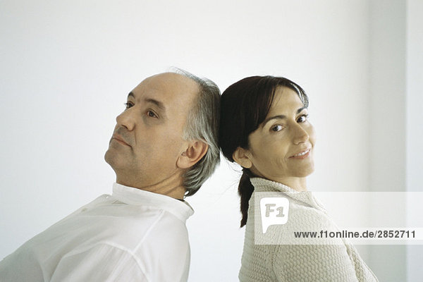 Mature couple standing back to back  leaning backwards  touching heads