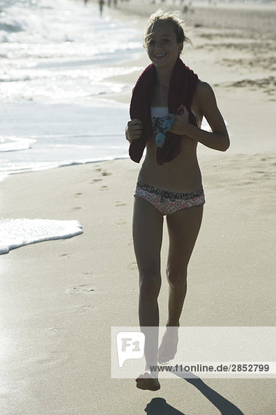 Teenagerin läuft am Strand  hintergrundbeleuchtet