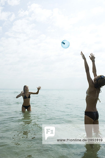 Teenager-Freunde spielen tief im Wasser mit Strandball