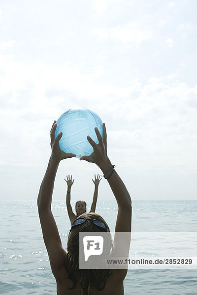 Teenagermädchen spielen mit Strandball im Meer