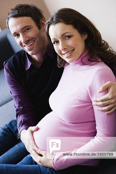 Pregnant woman and man sitting on couch