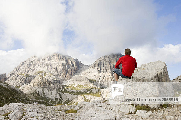 Man sitting on rocks looking at peaks