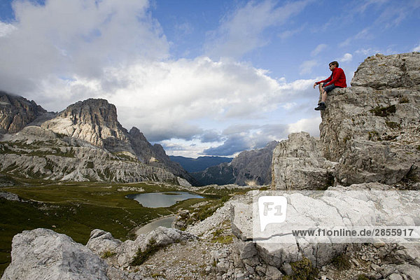 Mann auf Berggipfel sitzend