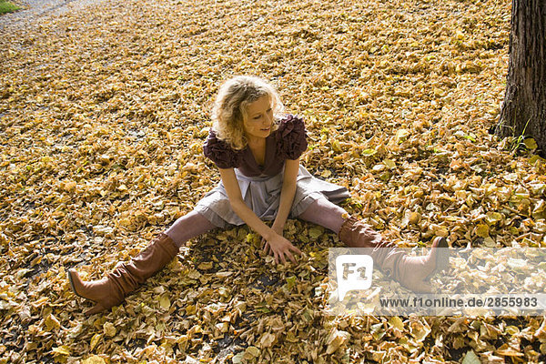 Woman sitting within heaps of leaves