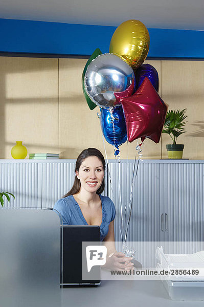 Junge Frau mit Ballons am Schreibtisch