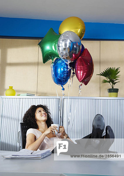 Junge Frau mit Ballons im Büro