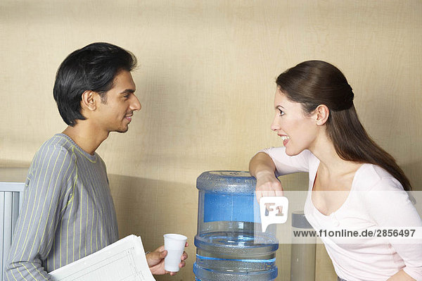 Mann und Frau beim Plaudern mit Wasserkühler