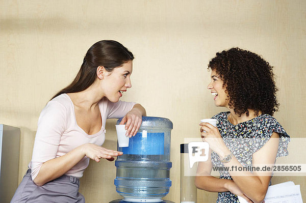 Zwei Frauen plaudern mit einem Wasserspender.