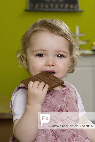 Young girl biting into chocolate bar