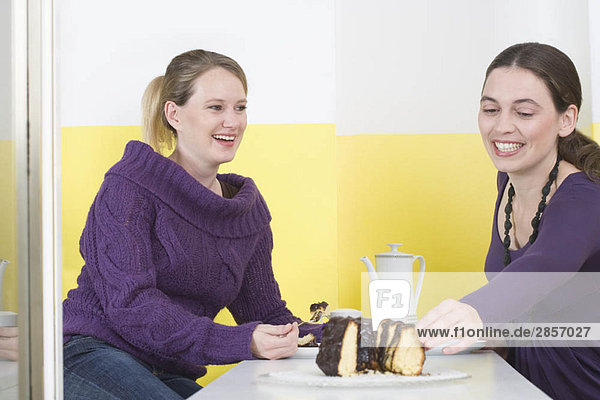 Zwei junge Frauen  die Kuchen essen.