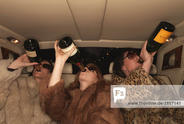 Drei Frauen trinken Champagner im Auto