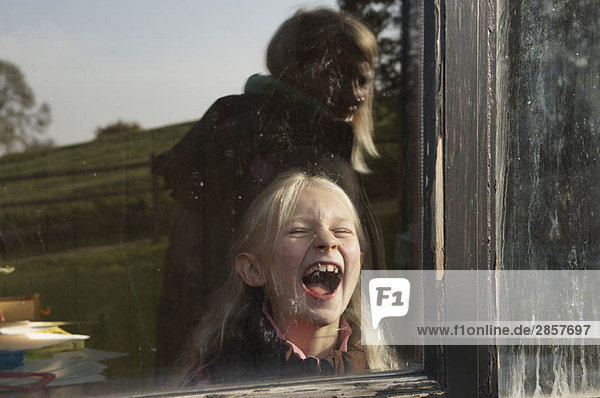 Mädchen lacht durchs Fenster
