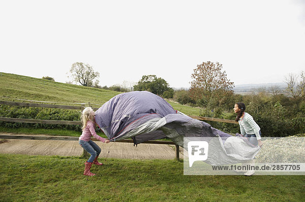 Zwei Mädchen bauen ein Zelt auf