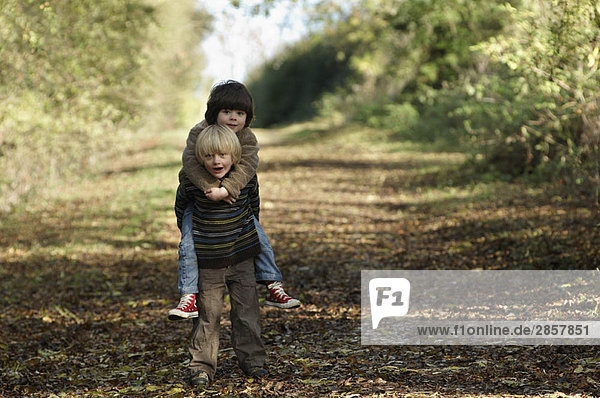 Young boy carrying friend in countryside