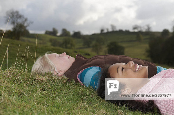Two girls lying on grass looking at sky