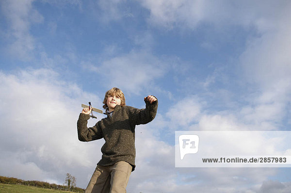 Boy with toy plane in countryside