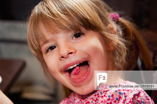 Mädchen mit rosa Süßigkeiten auf der Zunge